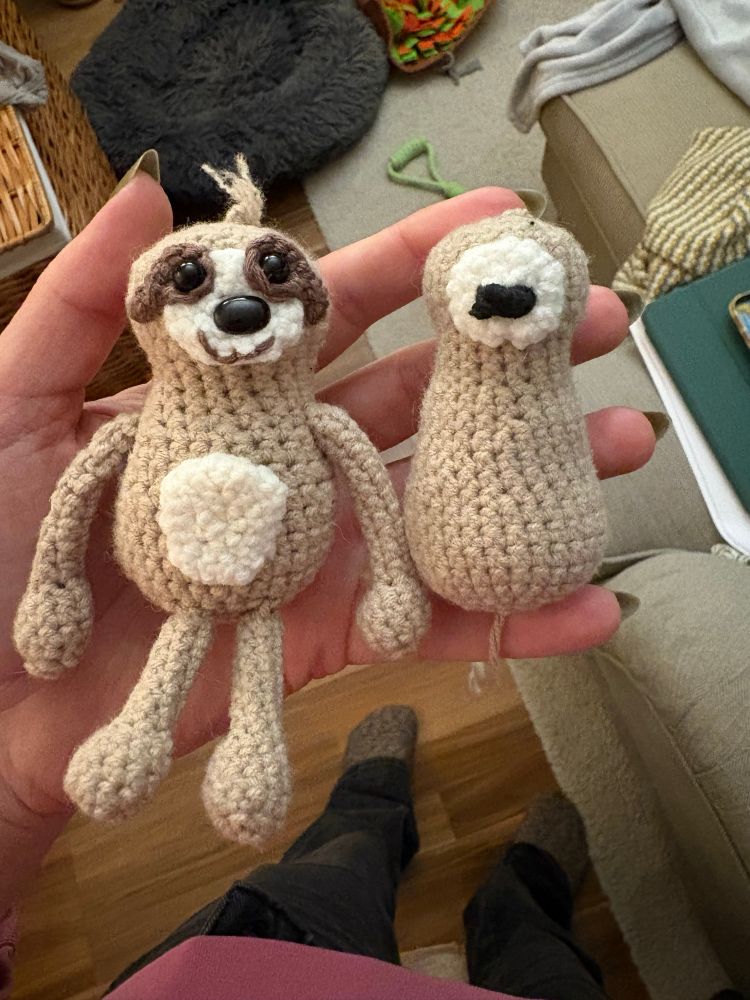 Ein kleines gehäkeltes Faultier und ein angefangenes Faultier, bei dem bisher nur der Körper, das Gesicht und die Nase fertig ist 