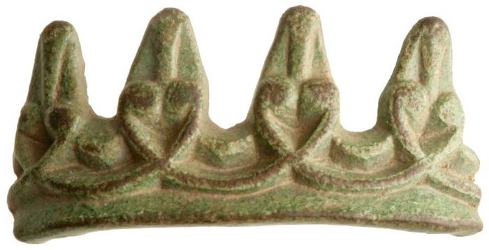 A finds photograph of a small, broken copper-alloy fitting from the site of the Great Army camp at Torksey, Lincolnshire. This is DB number 130: it's part of a carved, slightly curved ferrule, with projecting dags on one side forming shapes reminiscent of animal masks.