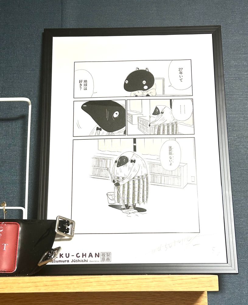 漫画バクちゃんの複製原画を額装してかざっています。
漫画のページは、地球に27年ほど住んでいる移民の宇宙人に、主人公のバクちゃんが「地球は好き？」とたずねています。
しばらく考えて、彼女はこう答えています。「選択肢　ないよ（ノー　チョイス）」という内容が4コマにわたって描かれています。