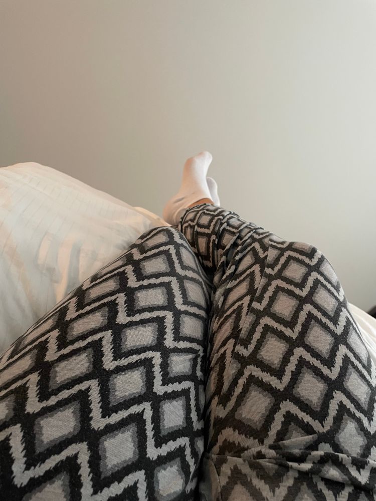 Bild på mina pyjamasklädda ben som är något upphöjda där jag ligger i sängen och tycker synd om mig själv. 