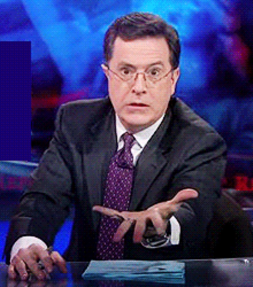 a man in a suit and tie is sitting at a desk with his hands out