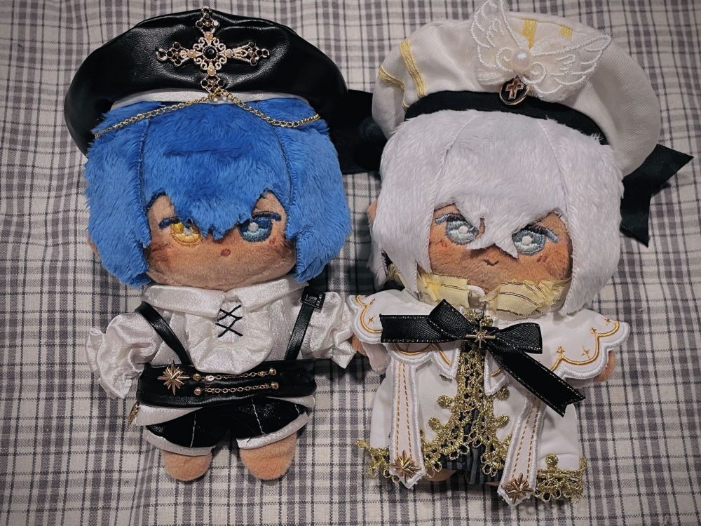 a photo of a pair of dolls based of characters from Metaphor Refantazio (Left is Will, Right is the Prince), both are dressed in monochromatic clothes against a monochrome plaid background