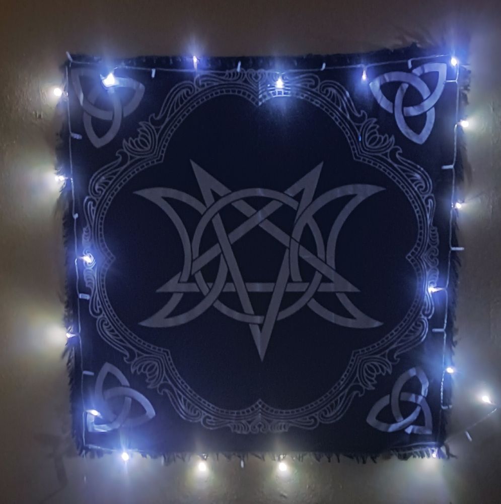 Tenture avec plusieurs symboles wiccans, entouré d'une guirlande électrique.