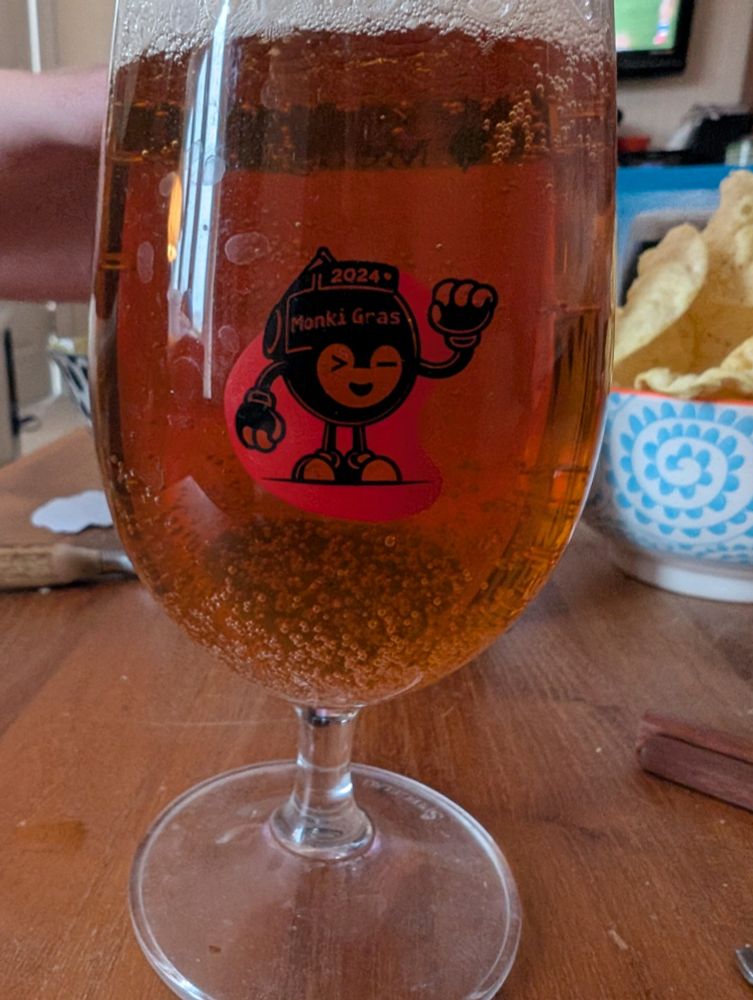 A Monkigras beer glass, filled with pale ale
