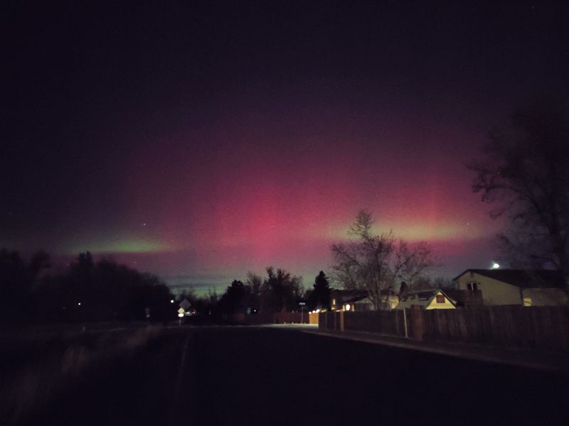 An aurora, visible to the eye, caught in a CO neighborhood. A green flare up cuts straight through the pink hue in the sky.