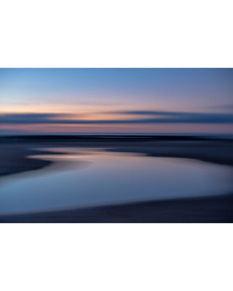 Impressionistic image taken post sunset with the colours in the sky reflecting off the sinuous curves of a pool left by the receding sea