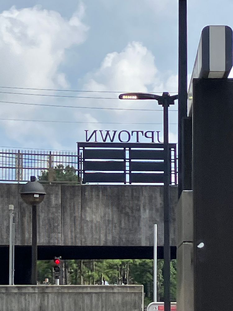 a sign read from behind (such that the letter is backwards) that says "UPTOWN"