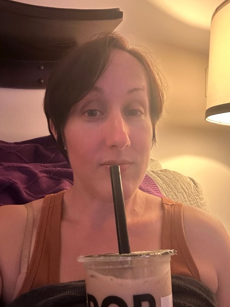 Picture of me with short auburn hair/side bangs, a brown tank top, and a pumpkin boba tea