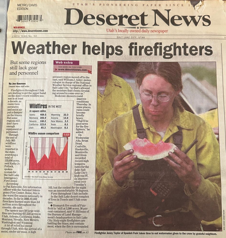 A very dirty firefighter wearing a yellow shirt holds a piece of watermelon. She is so intent on eating the watermelon, she has no idea her picture is being taken.