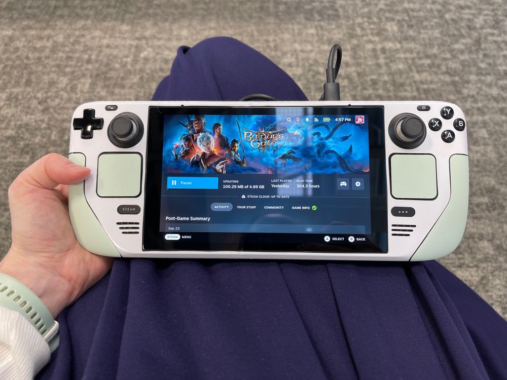 Steam Deck held in lap, screen shows Baldur's Gate 3 in Steam