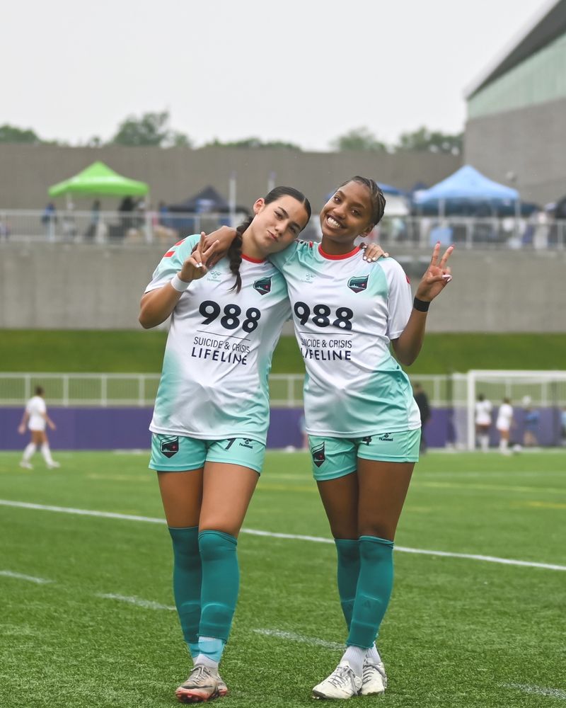 Photo of Saige Wimes and Kunie Hirai posing for a picture in their 988 Nami Mental Health jerseys. They are holding up the peace sign.