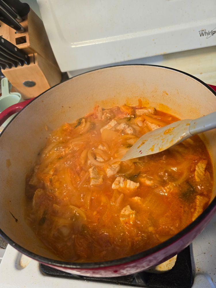 A giant pot of kimchi jjigae bubbling up on the stove