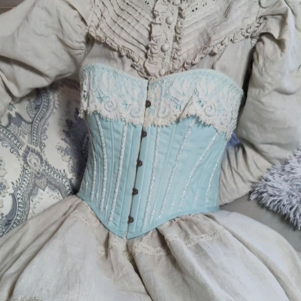 late 19th century style corset in pale blue with white antique lace on top edge and white and silver embroidery along boning channels