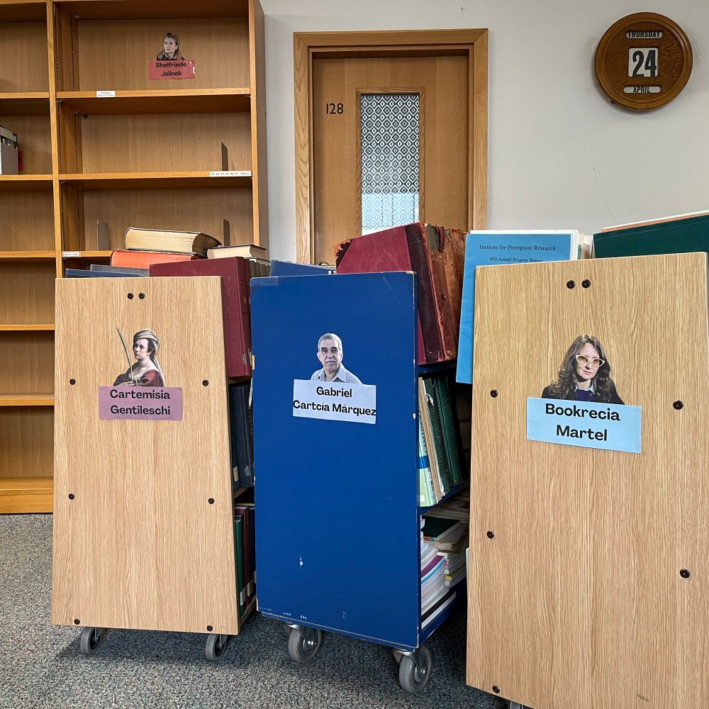 Book trolleys with the names Gabriel Cartcía Márquez, Bookrecia Martel and Cartemisia Gentileschi printed on the sides are displayed in the MMLL Library foyer.