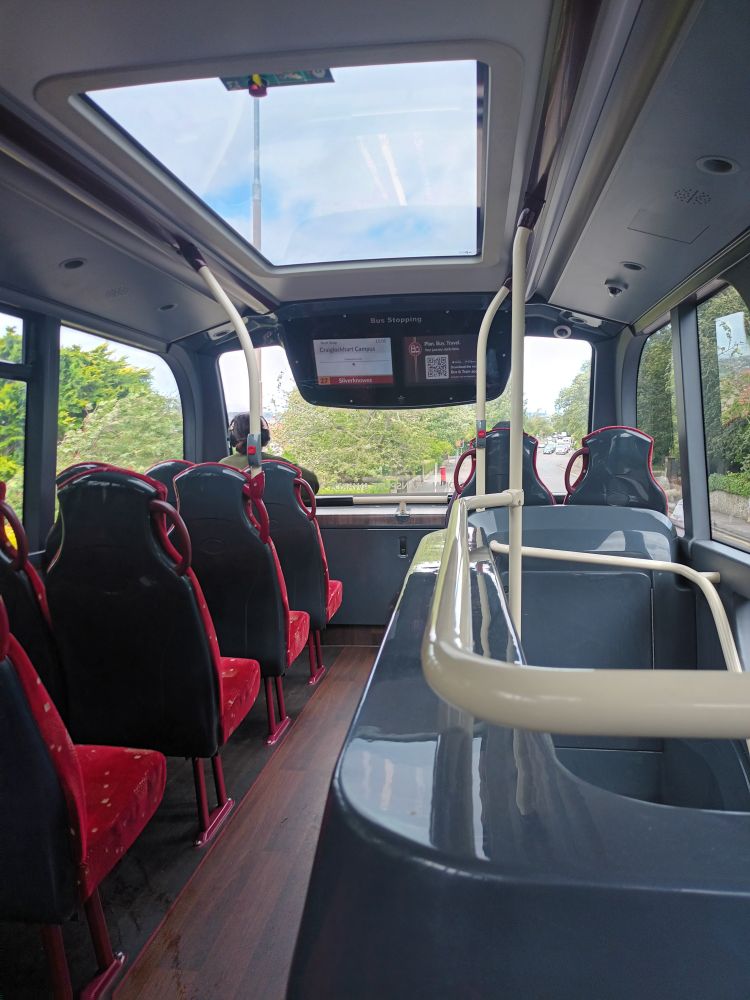 A forward view on the top deck of a bus from the seats just behind the staircase. These provide a panoramic view.