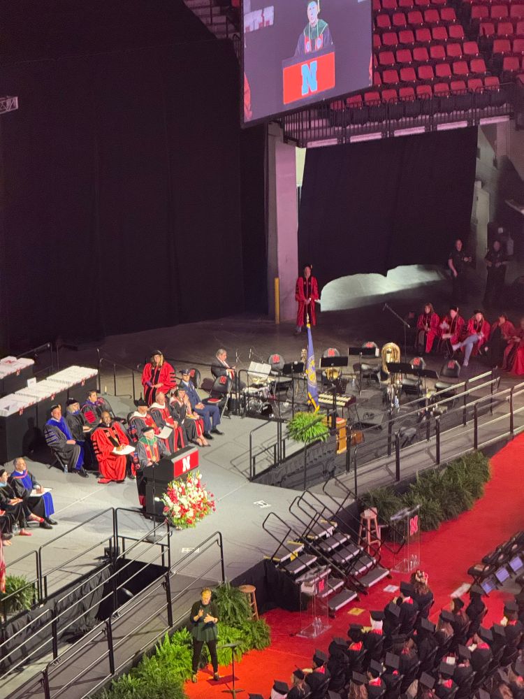 A photograph of the UNL commencement stage. Dr. Gold is speaking. 