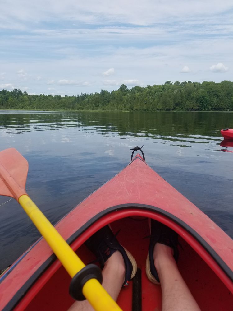 Clyde's hideously pale legs in a kayak floating on a calm pond