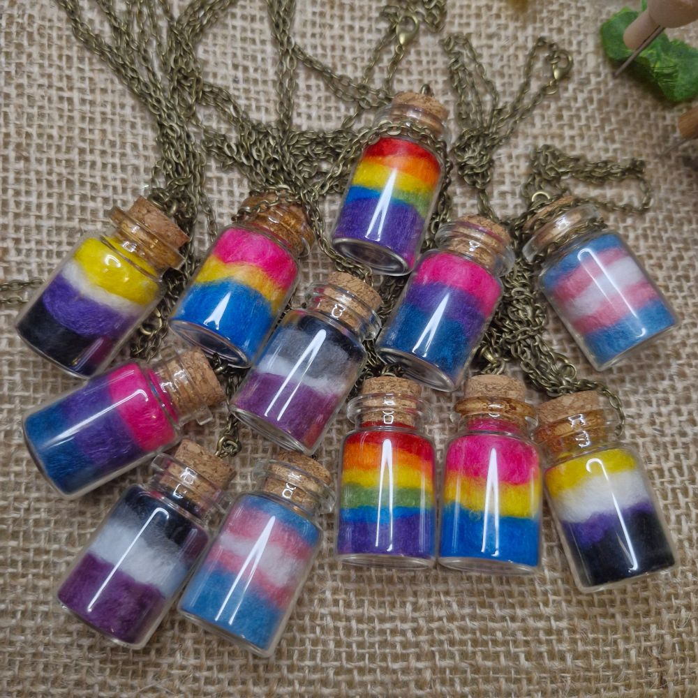 A bundle of glass bottle necklace pendants, each with different pride flag colours inside.