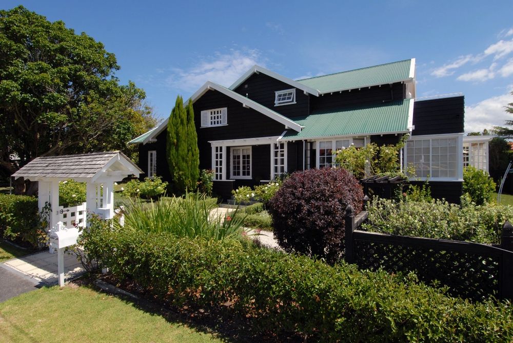 Black & white 1920s bungalow with lychgate and front garden taken from the street