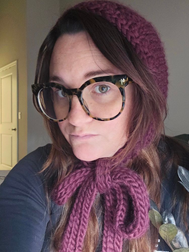 Girl wearing hand knitted bonnet purple.