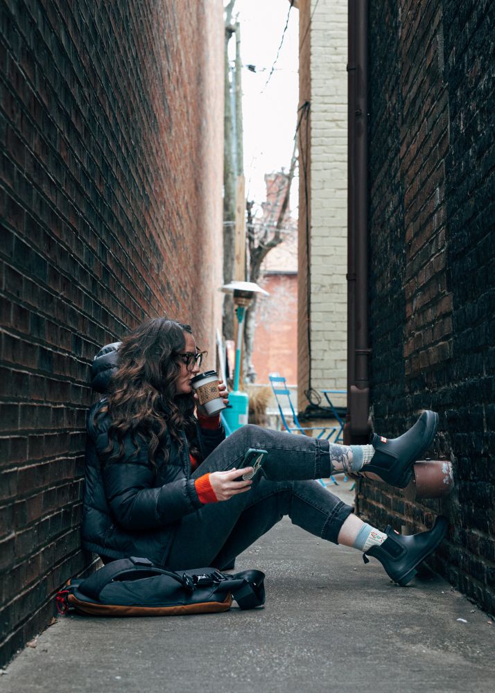 Myself sitting in a slightly dirty alleyway drinking coffee and researching art on my cellphone.
