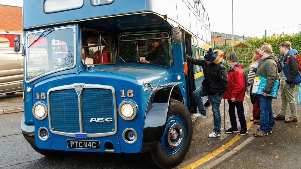 A vintage blue double deck bus picks up passengers outside the museum of transport. The bus is Leigh fifteen, one of the museum's fleet, and it's about to depart on one of the museum's heritage bus services.