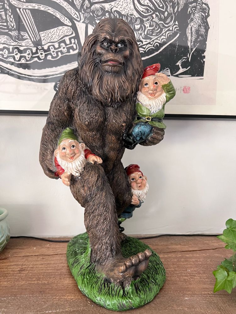 Close up of the most amazing figurine: Bigfoot carrying a couple of gnomes with another gnome clinging to one of his legs