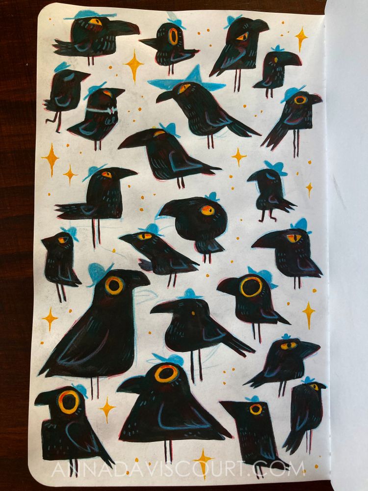 A sketchbook page full of simplified black crows with golden eyes wearing blue hats, surrounded by sparkles. Watermark: annadaviscourt.com