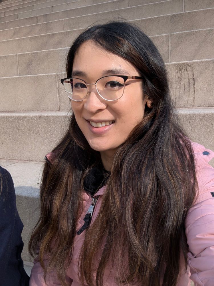 selfie of me in my pink coat in front of some concrete stairs, I'm smiling here 