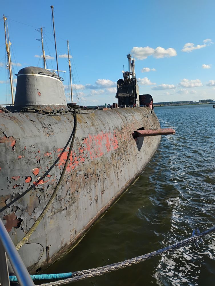 An old submarine on the surface with rust and peeling paint.