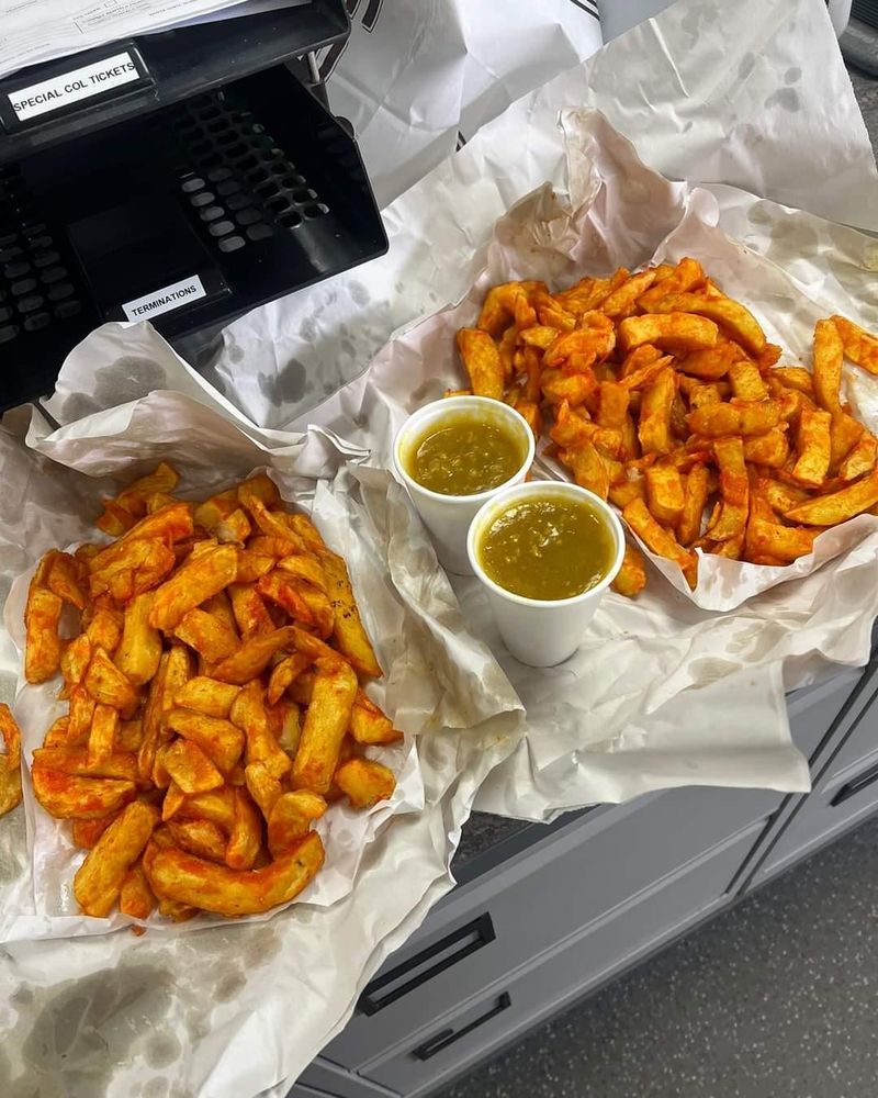 Two portions of battered chips (or 'orange chips') with two cartons of chipshop curry sauce.
