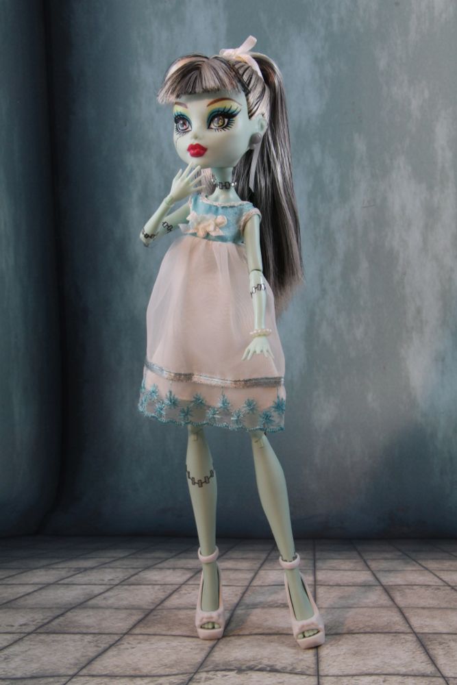 1st Gen Frankie Stein doll wearing a vintage pale blue Tutti dress on a grey background.