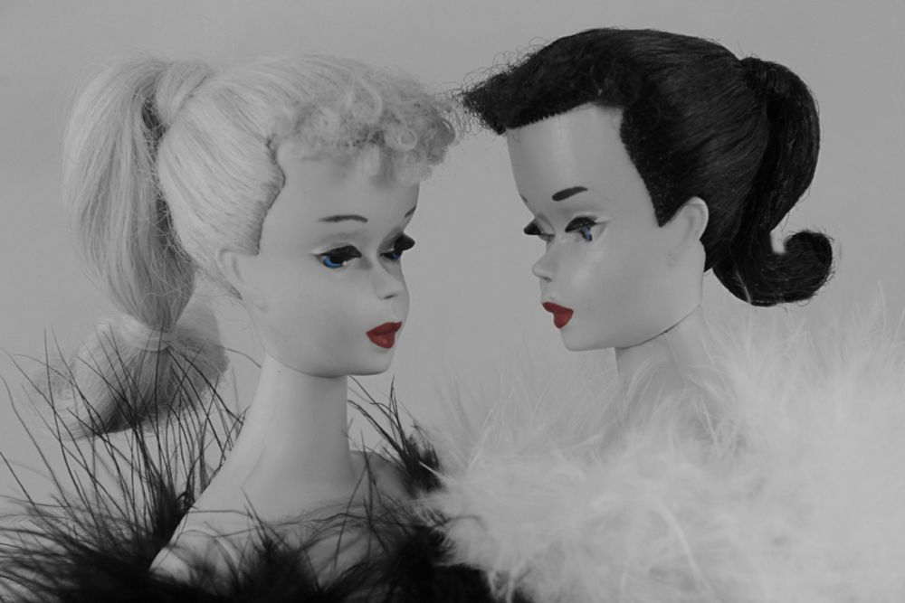 two vintage ponytail Barbies in black and white with red colored lips. One is a blond, one is a brunette.