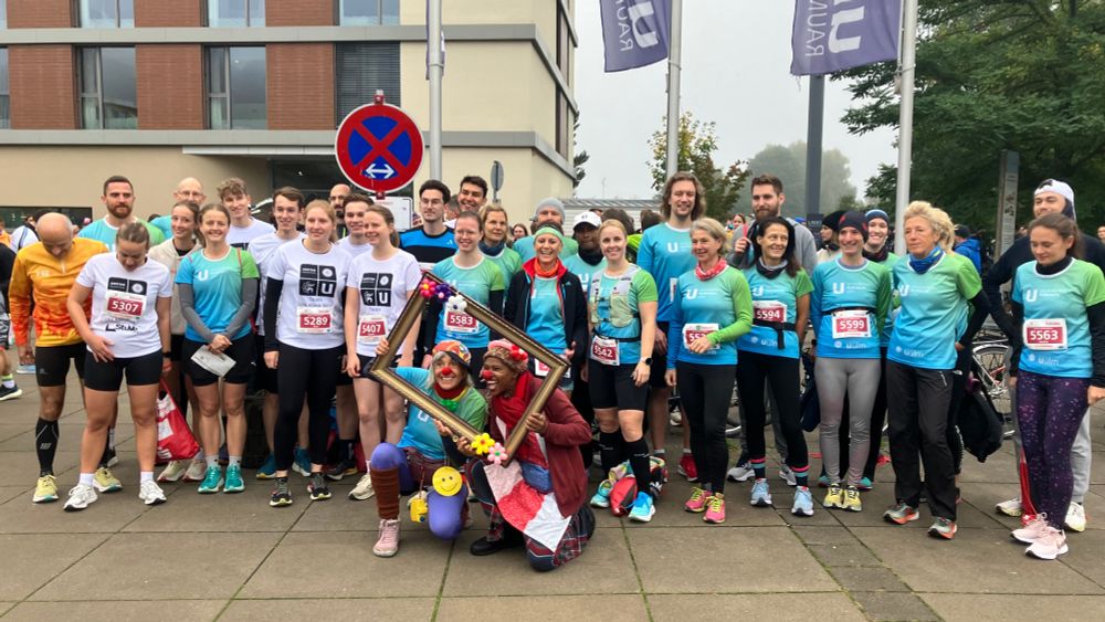 Gruppenfoto Team Uni.Klinik.RKU beim Einsteinmarathon. Laufende in Sportkleidung und Klinikclows