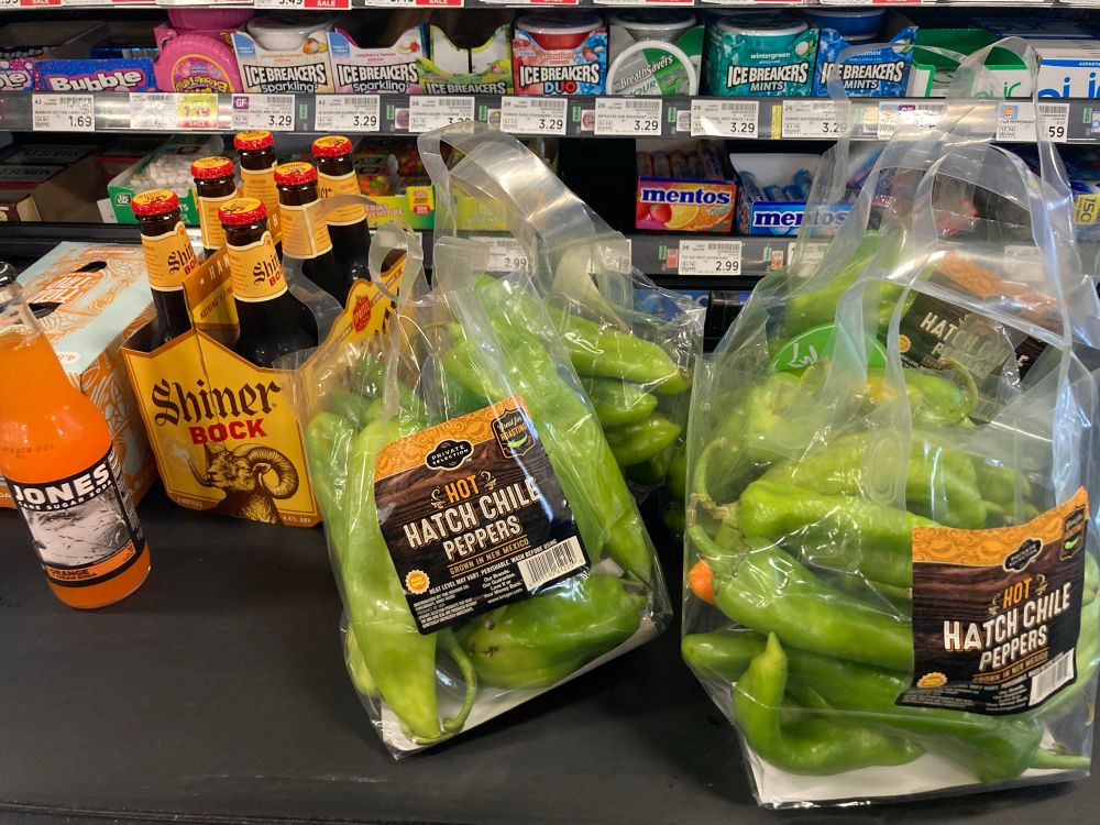 Bags of Hatch green chiles on the checkout rollers next to Shiner 