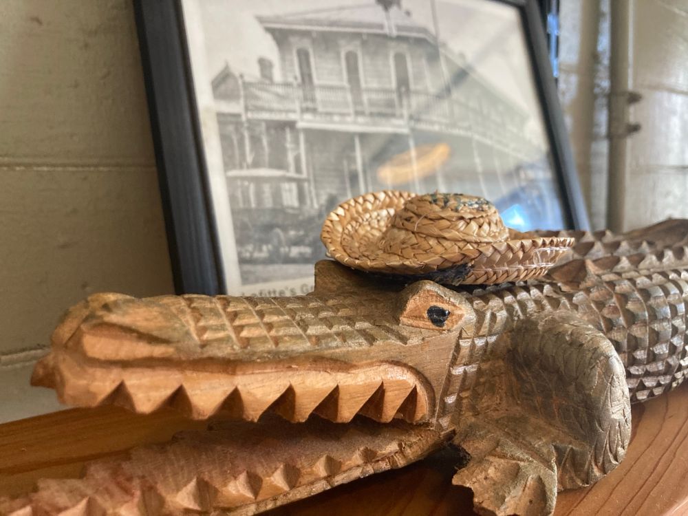 A carved wooden alligator wearing a straw hat
