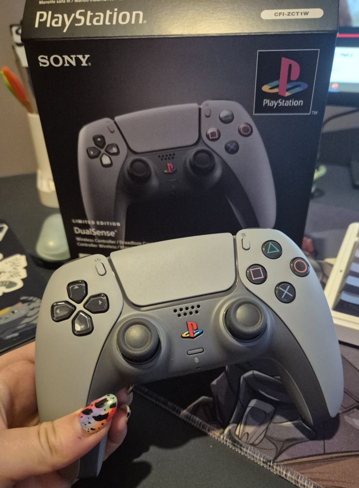 Playstation 30th anniversary controller being held infront of the box it came in