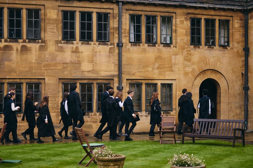 Students in academic dress walk through Nuffield College. Photo by David Fisher.