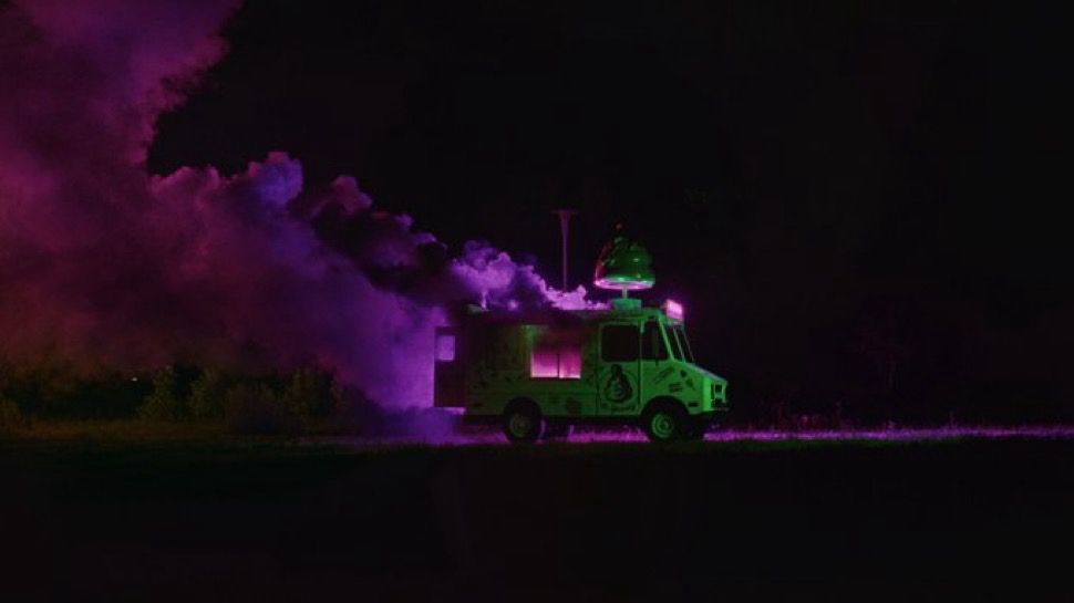 a neon lit photo with a green lit van with pink/purple/neon smoke billowing out of it 
