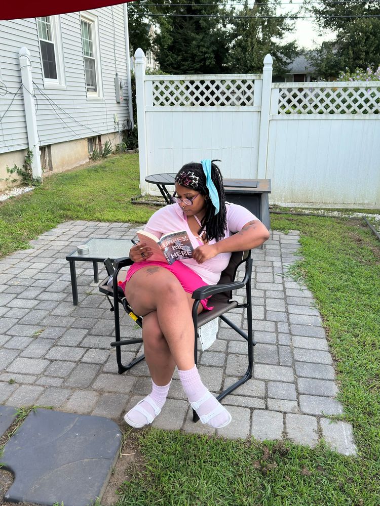 photo of salem sitting in her backyard reading unsex me here by Aurora mattia