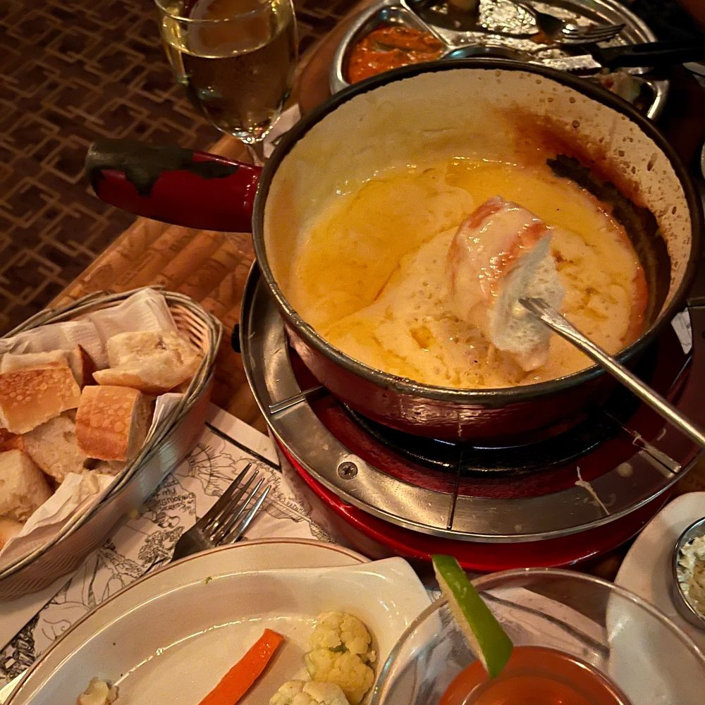 Cheese fondue with a piece of a baguette dipped into it.