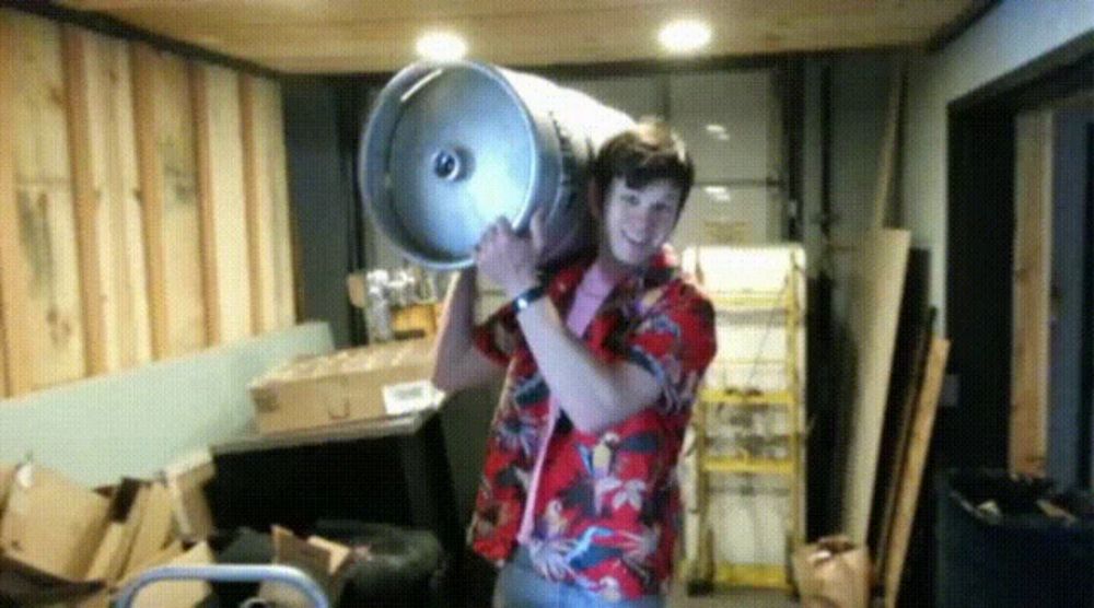 a man in a hawaiian shirt is carrying a large keg