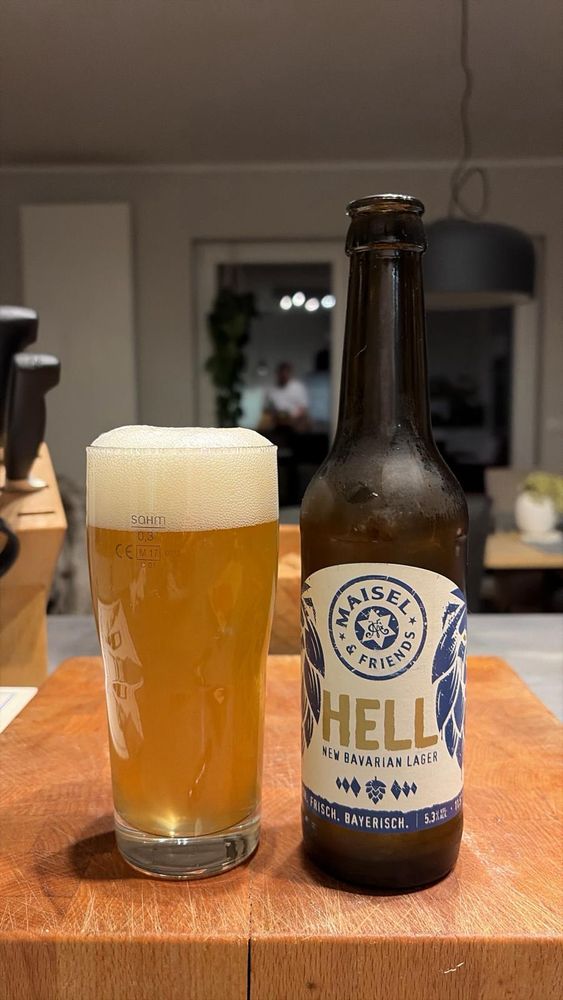 Ein volles Glas Bier neben einer Flasche Bier