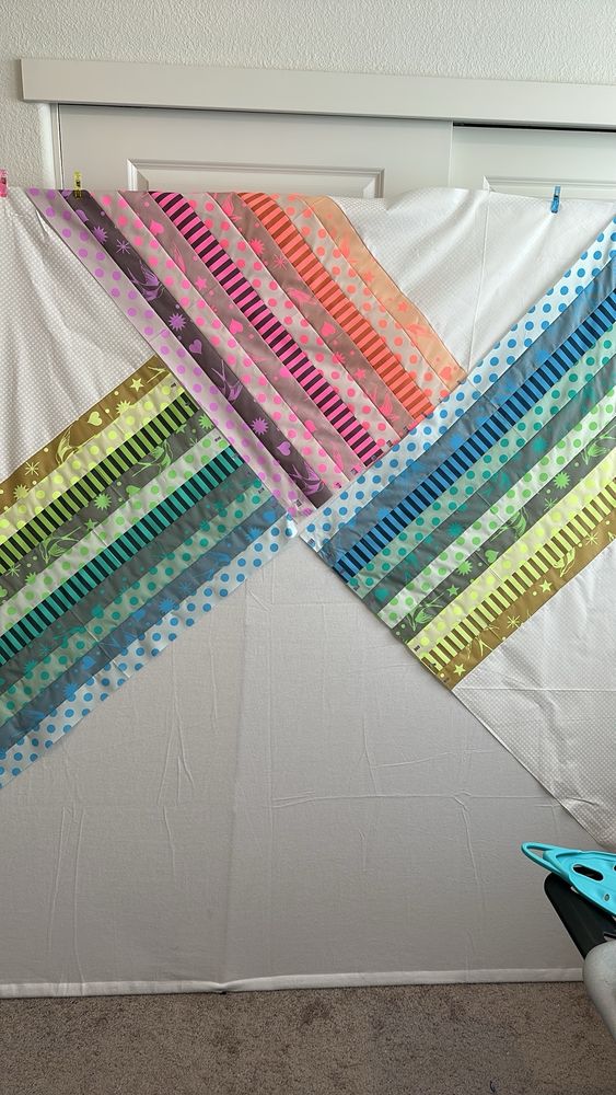 75% of a quilt, made out of strips of neon fabric and white triangles. 