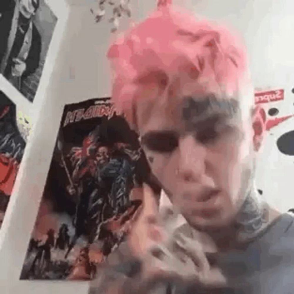 a man with pink hair and a tattoo on his face is standing in a room .