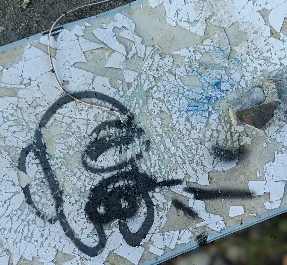 some kind of shattered flat screen discarded on the ground to which someone has artistically contributed a spray painted among us crewmate WITH dick and balls