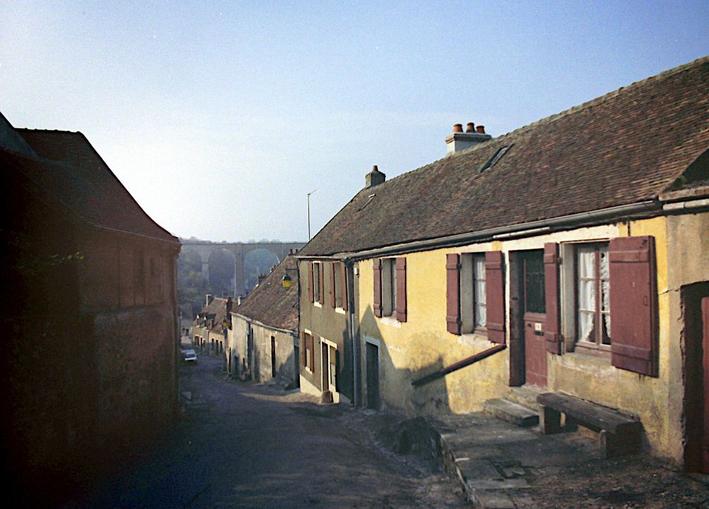 A French townscape, with a viaduct in the distance.