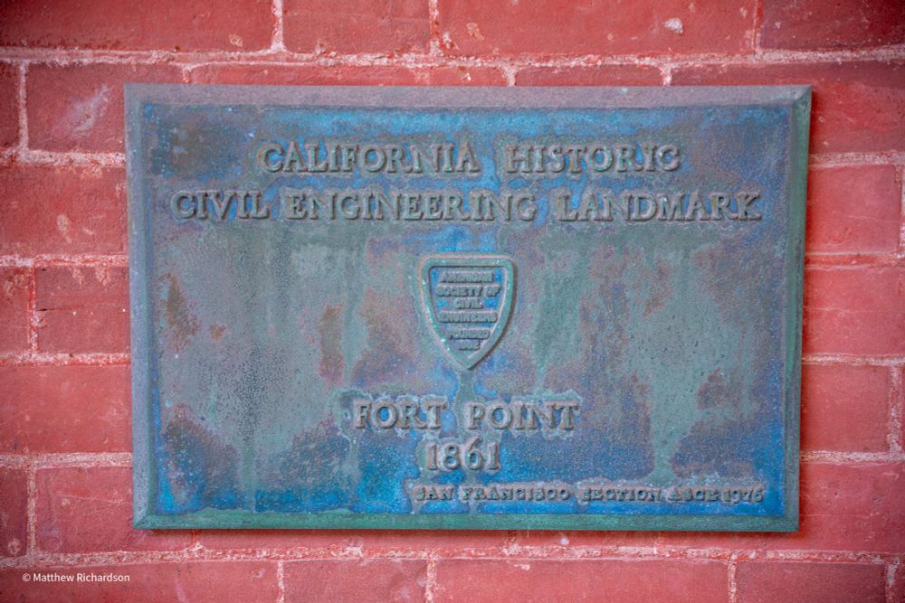 Plaque commemorating the California historic civil engineering landmark of Fort Point built in 1861. Red brick wall behind the plaque.
