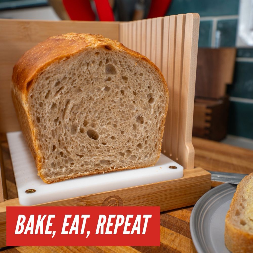 Cross section of a loaf of sourdough sandwich bread exposing a moderately open crumb. Overlayed in the bottom left corner is the text “bake, eat, repeat”. In the bottom right corner there is a corner of a piece of sliced bread with butter on top. 