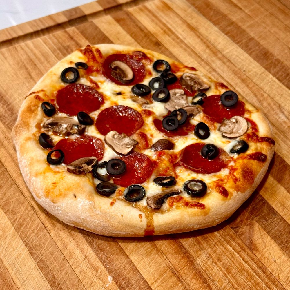 Homemade pizza with pepperoni, mushrooms and olives. Roughly 12” in diameter. 